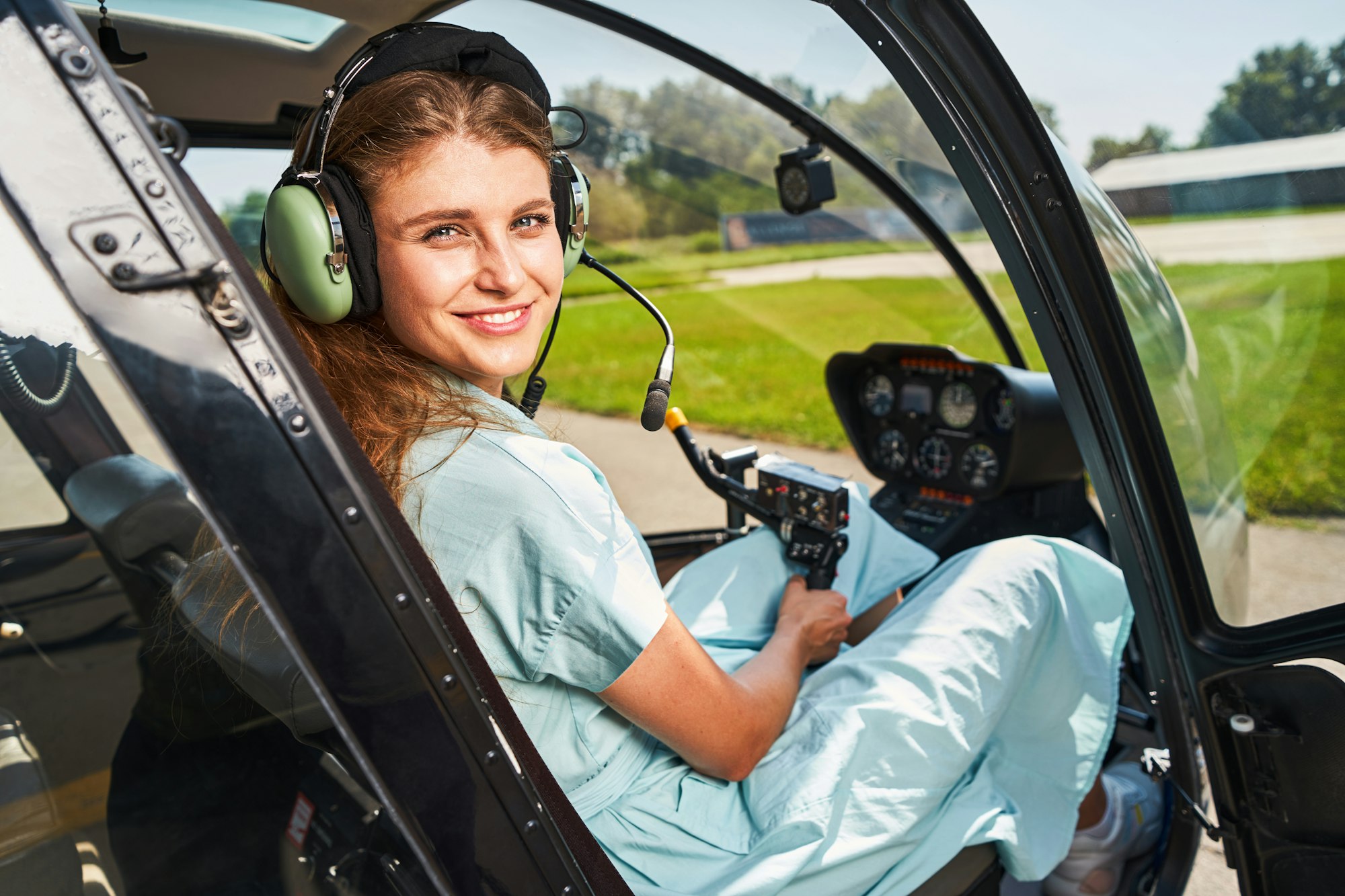 Joyous airwoman sitting in cockpit of private chopper